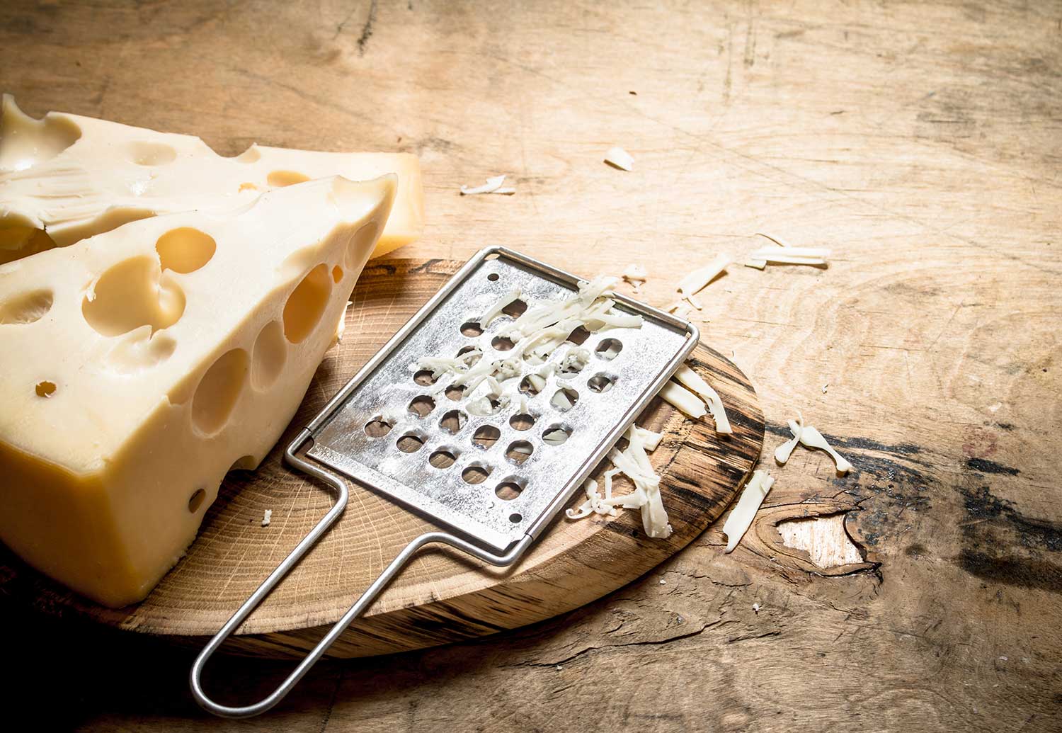 piece of cheese with grater on a board 